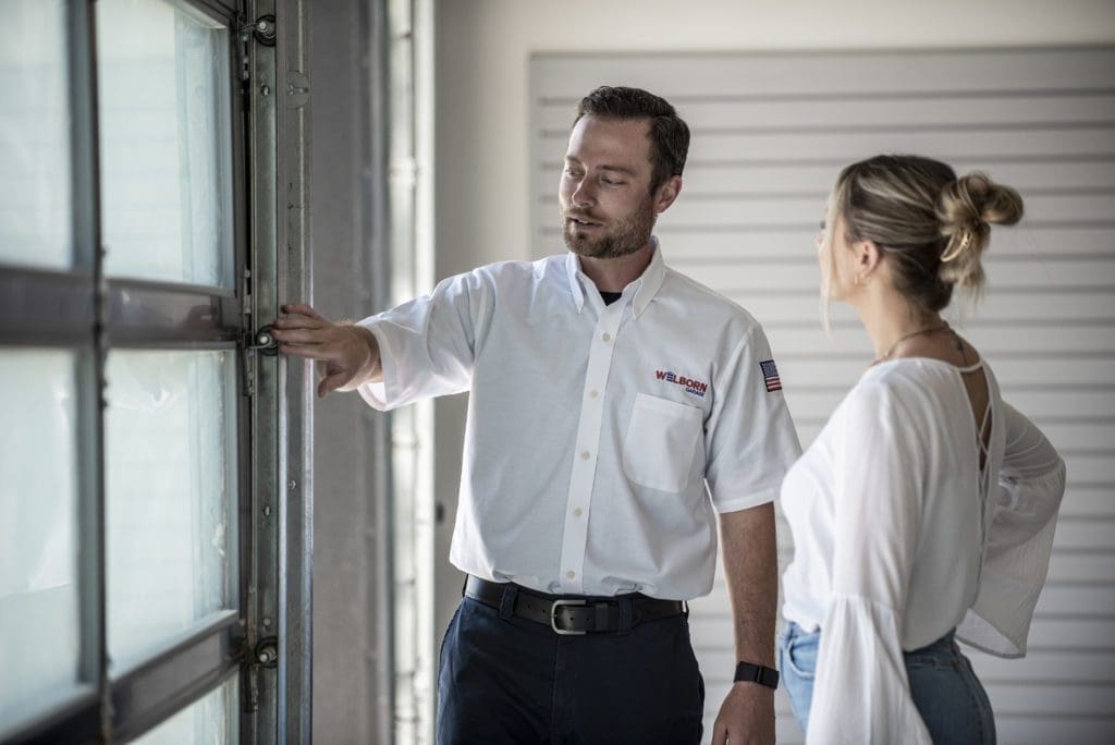Welborn Professional Technician Helping customer in front of garage door